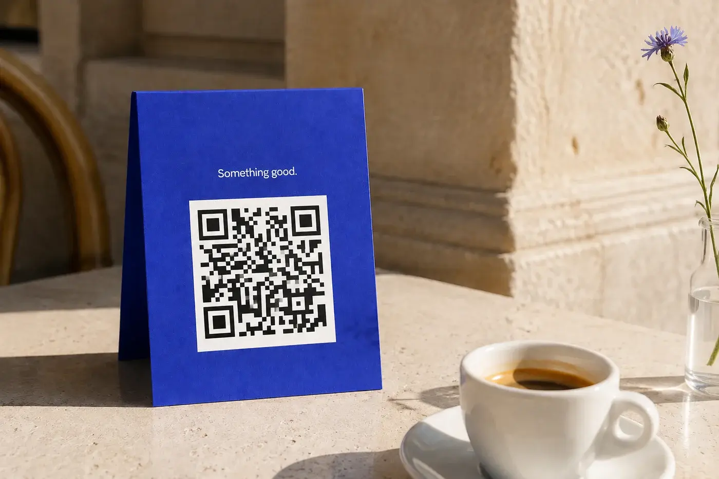 Illustrative blue QR menu card beside an espresso on a café table